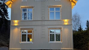 Una casa de dos pisos con numerosas ventanas y un exterior bien iluminado.