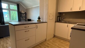 Una cocina moderna con armarios blancos, encimera de madera y una ventana con cortinas.