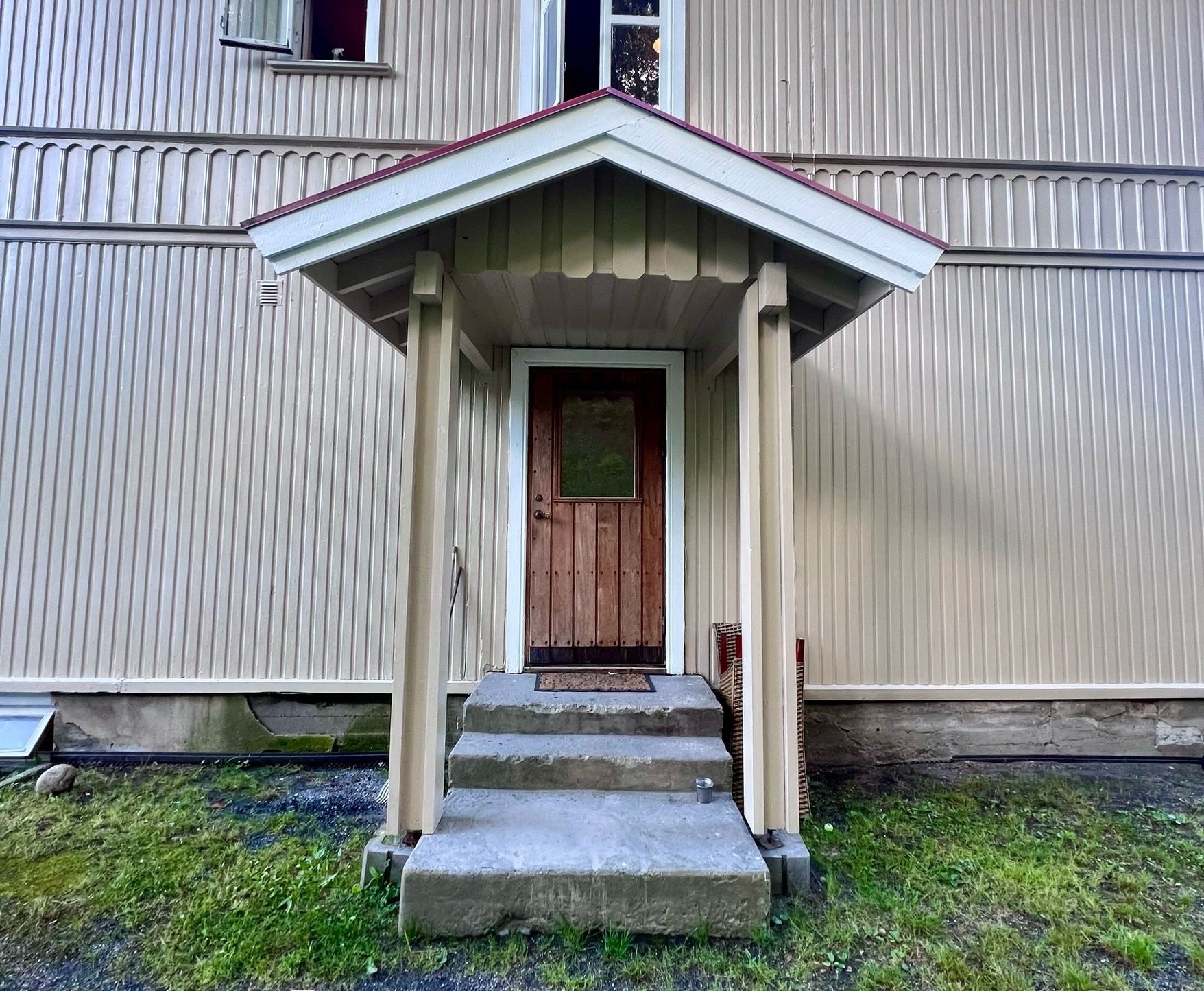 A building with a porch, a door, and steps leading up to it.