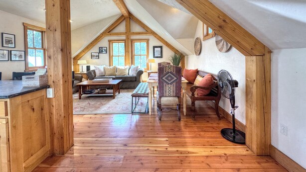 Un loft amplio con vigas de madera a la vista, una cama de altillo, zona de comedor y un rincón de estar acogedor con chimenea.
