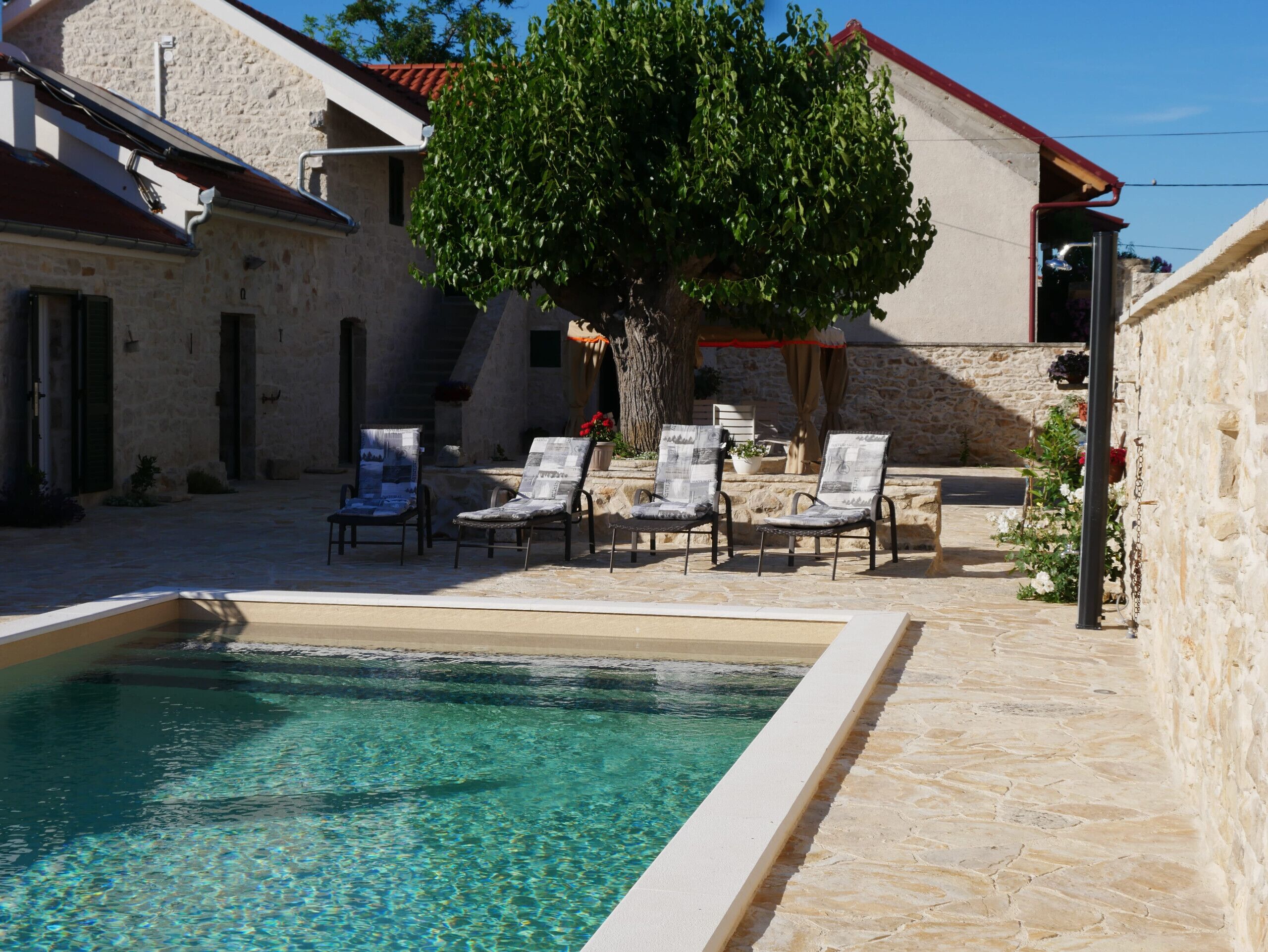A pool area with clear water, stone walls, and lounge chairs.