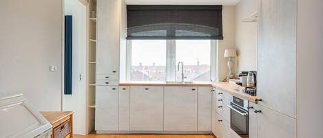 A modern kitchen with a large window, built-in cabinets, and a wooden floor.