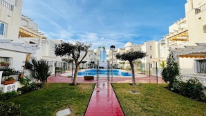 Un quartier résidentiel doté d’une piscine, de bâtiments blancs et d’un chemin rouge.