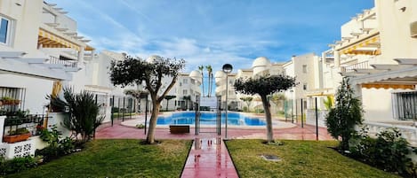 Et boligområde med swimmingpool, hvide bygninger og en rød sti.
