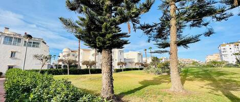 A residential area with modern buildings, a grassy lawn, and a few trees.