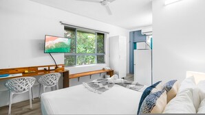 Habitación de hotel moderna con cama, escritorio, televisión y ventana con vista a zonas verdes.