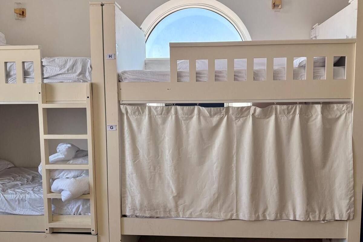 Une chambre avec un lit superposé, une lucarne et une petite fenêtre.