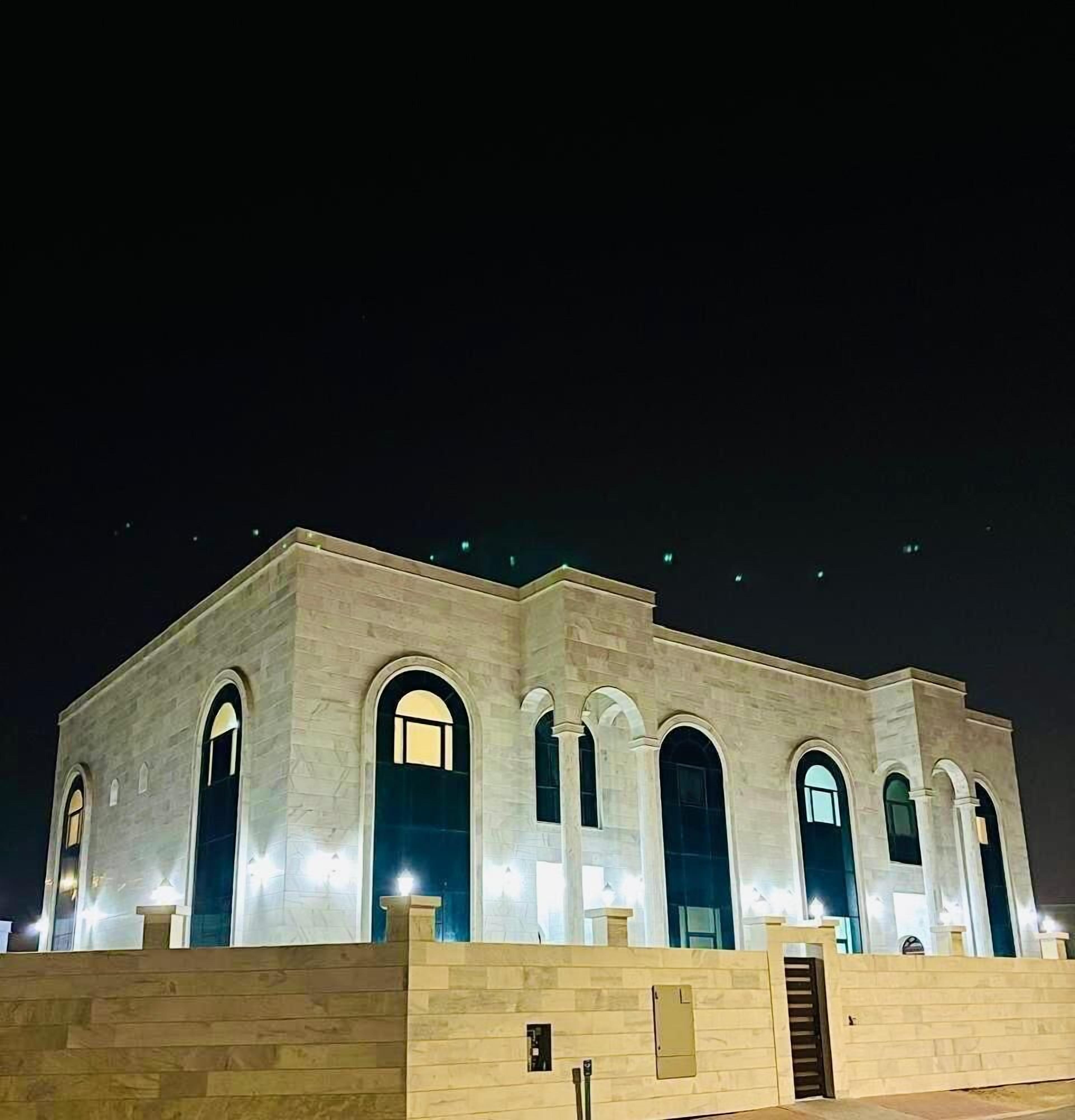 A large, well-lit building with multiple arched windows and a flat roof, likely a public or institutional building.