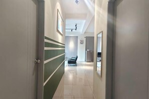 Un corridoio con una striscia verde al muro, un letto e uno specchio.