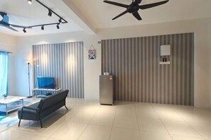 Una camera d'albergo moderna con TV a schermo piatto, divano, ventola a soffitto e parete a righe.
