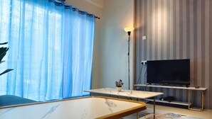 A room with a flat-screen TV, a table, a lamp, and a view of the outdoors. - Pavilionvillie M1T584 by Irainbow (Kinta)