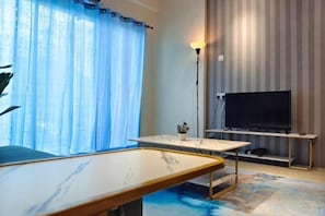 A room with a flat-screen TV, a table, a lamp, and a view of the outdoors. - Pavilionvillie M1T584 by Irainbow (Kinta)
