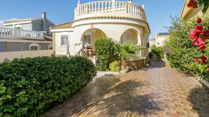 Un patio con un edificio curvo, un sendero de baldosas y vegetación.