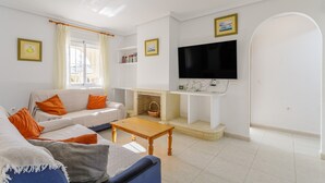 Una sala de estar con sofá, mesa de centro, televisor, chimenea y vistas al balcón.