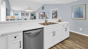 A modern kitchen with a large island, white cabinetry, and a stainless steel sink. - TB 37C Spacious 3-Bed, 2-Bath Second-Floor Condo in True Blue Community (Pawleys Island)