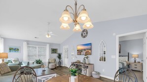 A spacious living room with a wooden dining table, comfortable seating, and a ceiling fan. - TB 37C Spacious 3-Bed, 2-Bath Second-Floor Condo in True Blue Community (Pawleys Island)