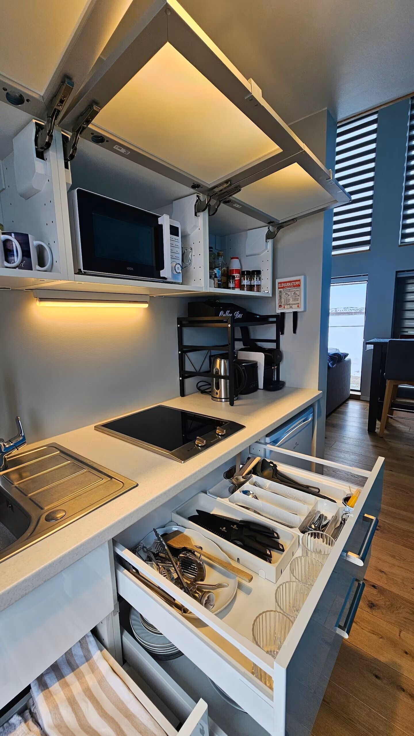 Ett kök med inbyggd mikrovågsugn, kaffemaskin och en kaffestation.