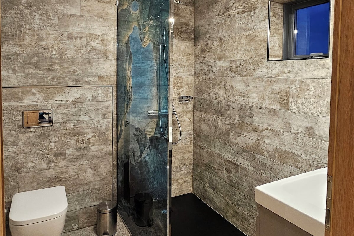 A modern bathroom with a shower, toilet, and sink.