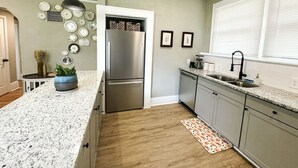 A kitchen with a stainless steel refrigerator, granite countertops, and a patterned rug. - The Duchess:Vintage Revived-Pets Welcome (Jacksonville)