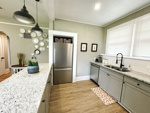 A kitchen with a stainless steel refrigerator, granite countertops, and a patterned rug. - The Duchess:Vintage Revived-Pets Welcome (Jacksonville)