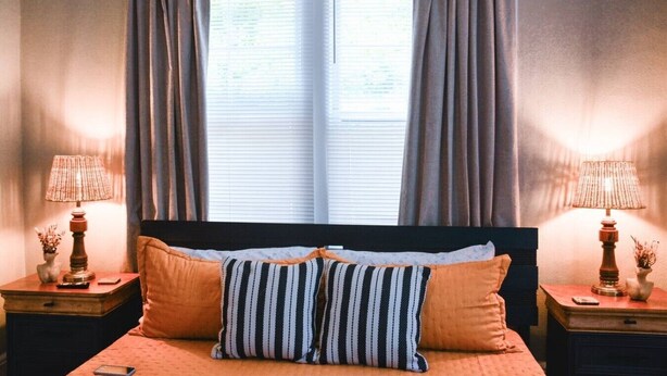 A bedroom with a bed, two nightstands, a window with curtains, and two lamps. - The Duchess:Vintage Revived-Pets Welcome (Jacksonville)