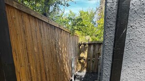 A narrow outdoor pathway with a wooden fence on one side and a concrete wall on the other. - The Duchess:Vintage Revived-Pets Welcome (Jacksonville)