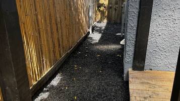 A narrow outdoor pathway with a wooden fence on one side and a concrete wall on the other.