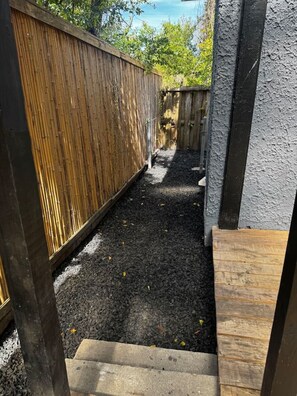 A narrow outdoor pathway with a wooden fence on one side and a concrete wall on the other. - The Duchess:Vintage Revived-Pets Welcome (Jacksonville)