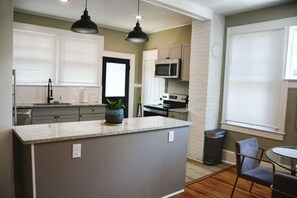 Una cocina moderna con encimeras de granito, una isla central y un comedor con una mesa redonda y sillas.