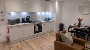 Una cocina moderna con armarios blancos, horno empotrado y comedor con mesa y sillas.