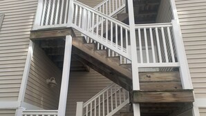 Eine mehrstufige Holztreppe mit weißen Geländern, die zu einer oberen Etage führt.