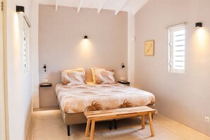 A bedroom with a bed, bedside tables, a bench, a window, and wall-mounted lights. - Bunitesa di bida Kas Iquana (Soto)