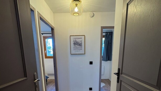 A hallway with wooden flooring, a framed picture on the wall, and a ceiling light fixture. - T3 apartment 50 meters from the slopes - Heart of the resort. (Les Deux Alpes)