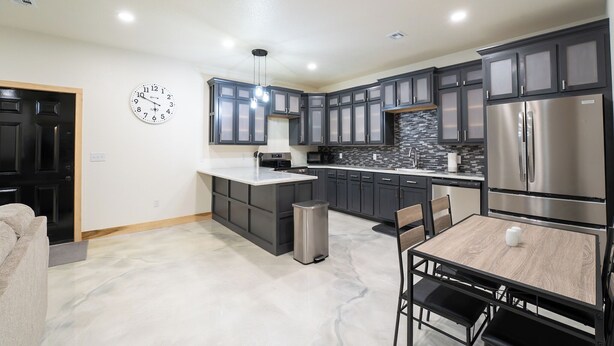 A modern kitchen with dark cabinets, a stainless steel refrigerator, and a central island. - Country Condo
 2-bedroom  with AC in Carl Junction (Carl Junction)