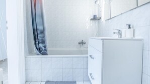 Un baño moderno con bañera, tocador con espejo y cortina de ducha.