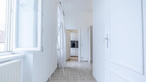 Un pasillo con paredes blancas, un radiador y una ventana.