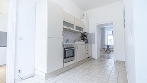 Una cocina moderna con armarios blancos, horno empotrado y cafetera.