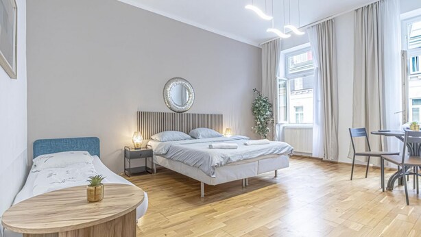 Una habitación de hotel moderna con cama, mesita de noche, lámpara y vistas a la ciudad.
