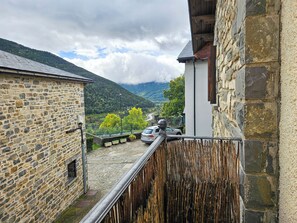 A stone building with a balcony overlooking a valley and mountains. - Apartamentos Casa Boira 3000 (Biescas)