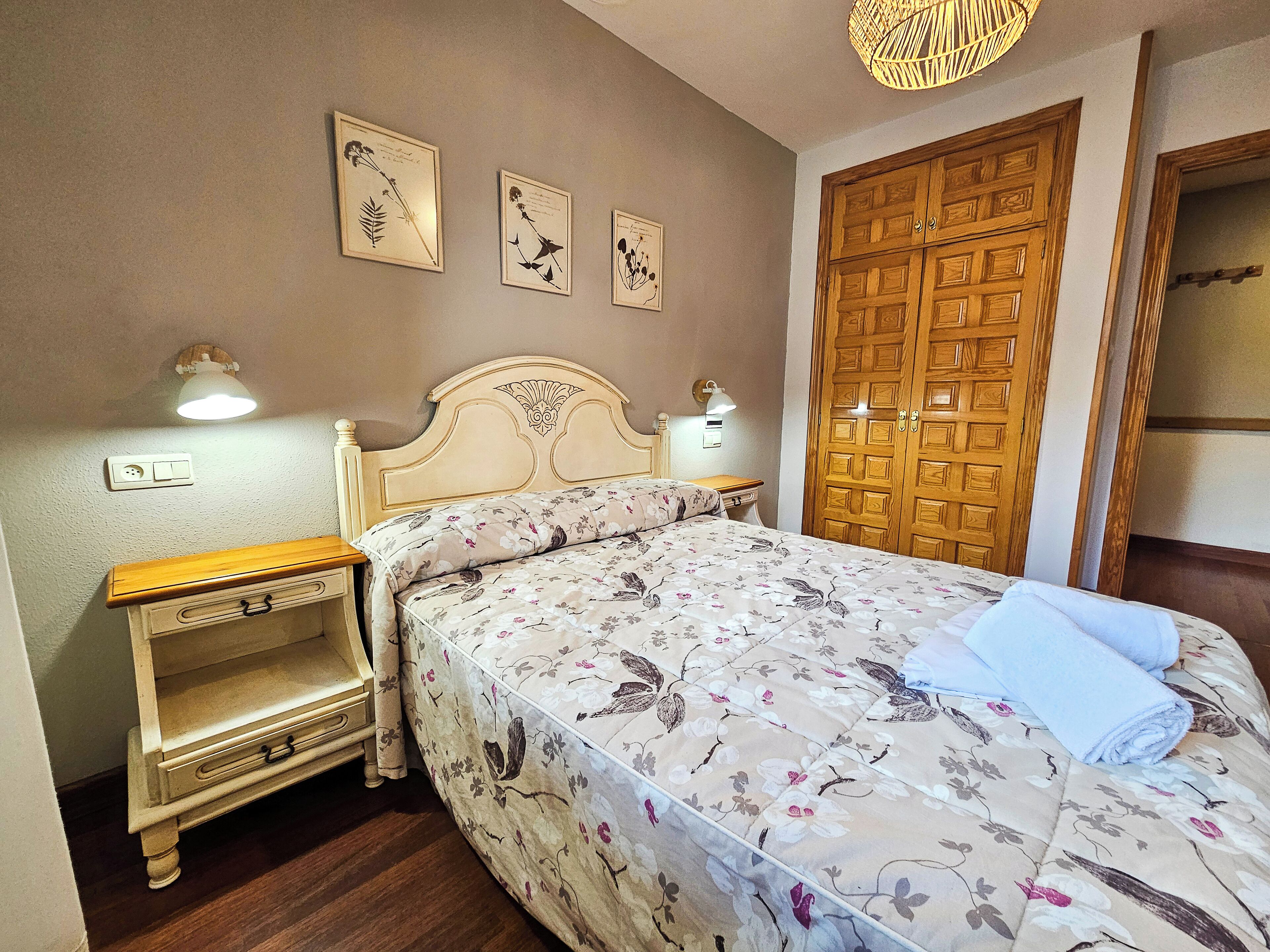 A bedroom with a wooden bed, a nightstand, a dresser, and a wooden wardrobe.