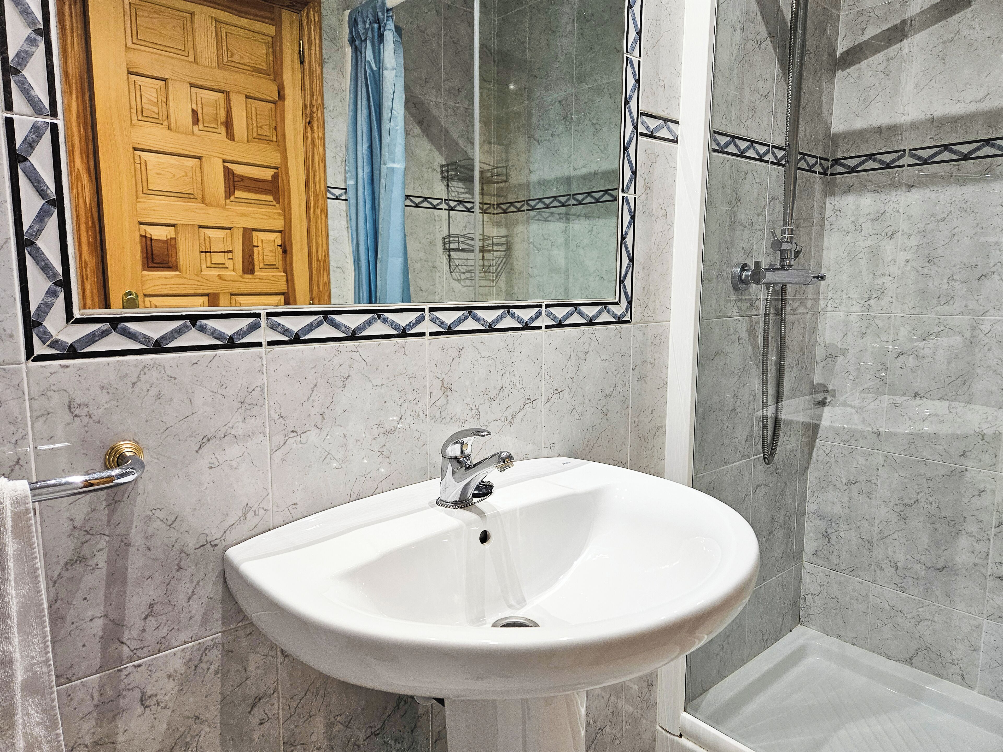 Une salle de bain avec un lavabo en marbre, une douche et une porte en bois.