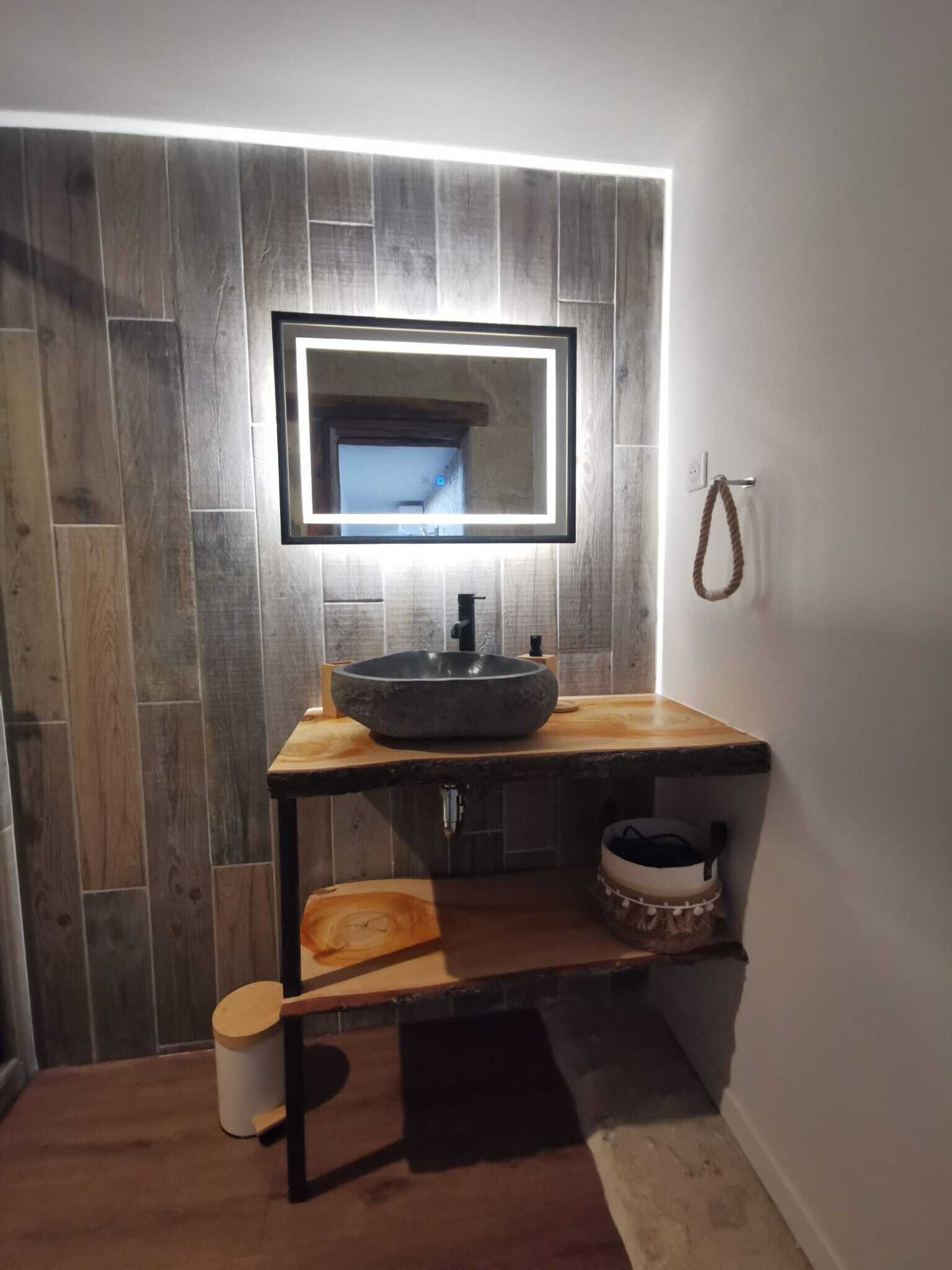 A bathroom with a wooden vanity, a large mirror, and a built-in sink.
