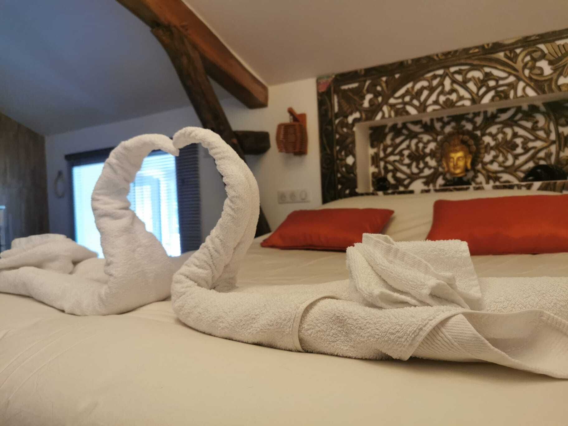A hotel room with a bed, red pillows, and a decorative headboard.