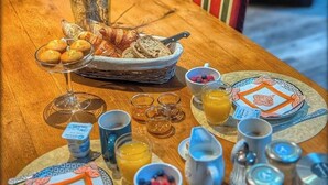 Ένα τραπέζι στρωμένο για πρωινό, με ψωμί, γλυκά και φρούτα πάνω σε μια ξύλινη επιφάνεια.