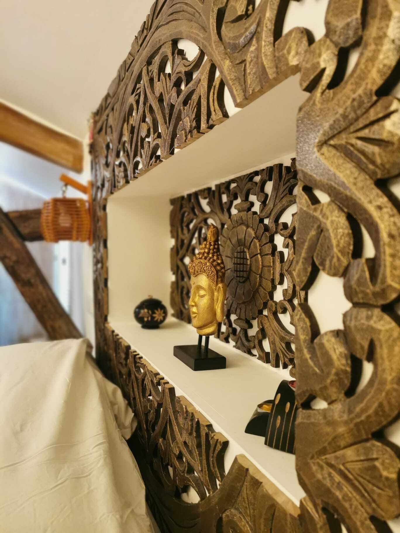 Una estantería con un marco de metal decorativo y una estatua dorada de Buda.
