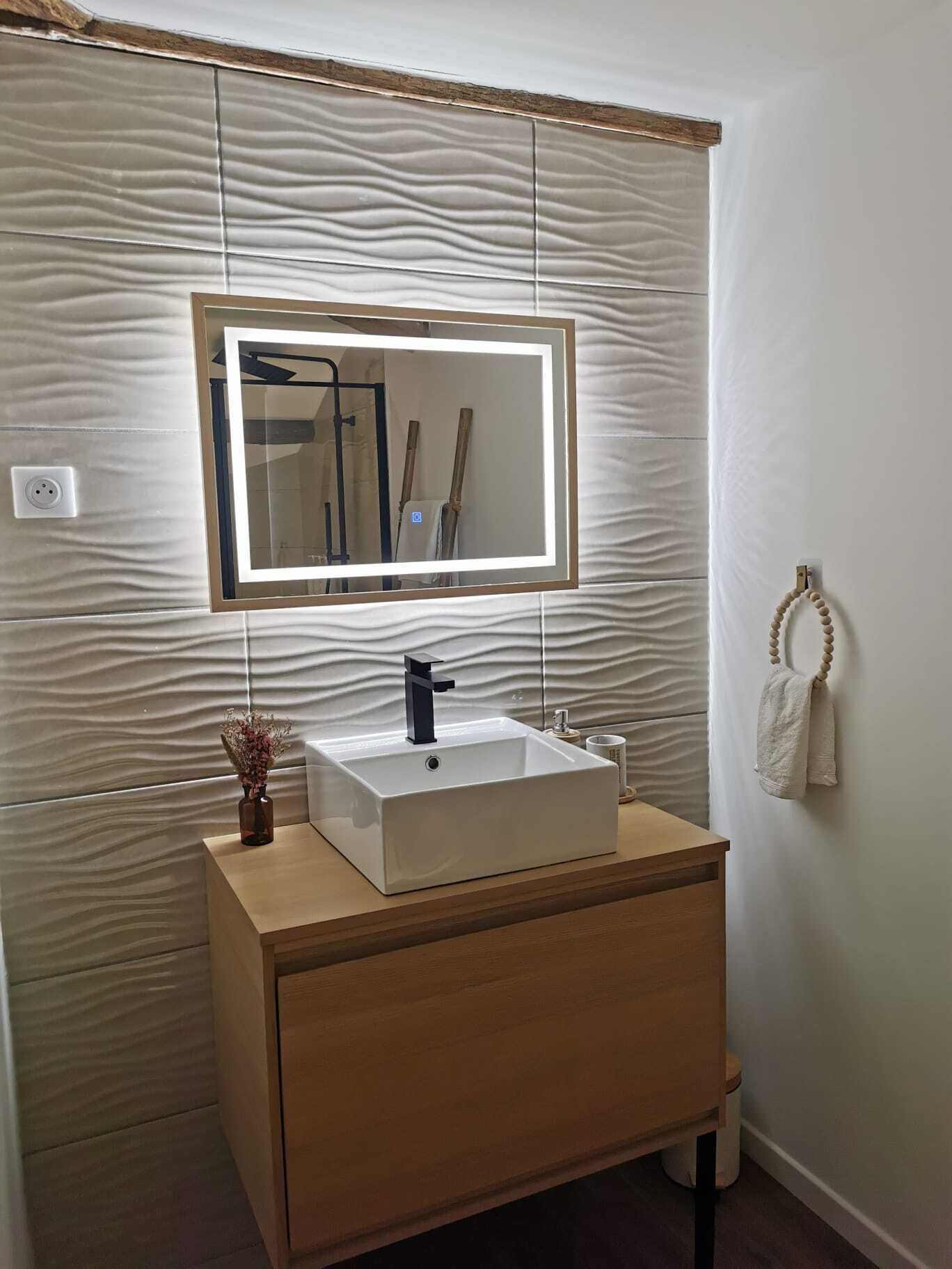 Un baño con un lavamanos rectangular, un espejo y un perchero para toallas.