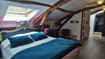 Un dormitorio con una cama grande, tragaluz, vigas de madera y una araña.