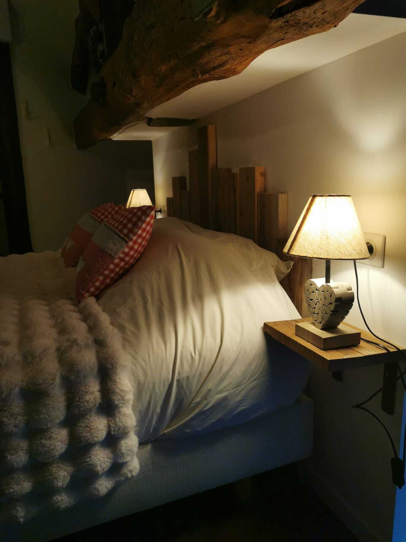 A bedroom with a bed, a nightstand with a lamp, and a wooden headboard.