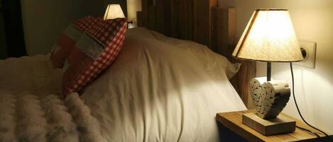 Un dormitorio con una cama, una mesita de noche con una lámpara y un cabecero de madera.