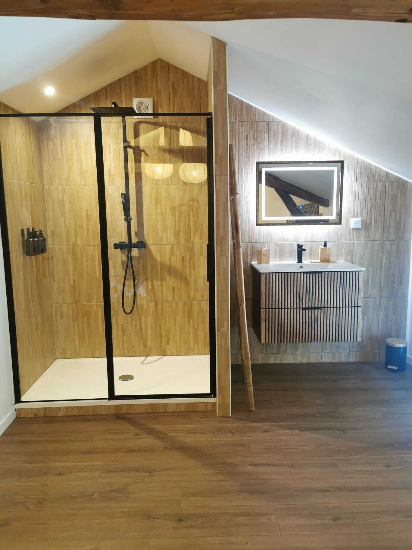 Un baño moderno con box de ducha de madera, tocador con espejo y suelo de madera.